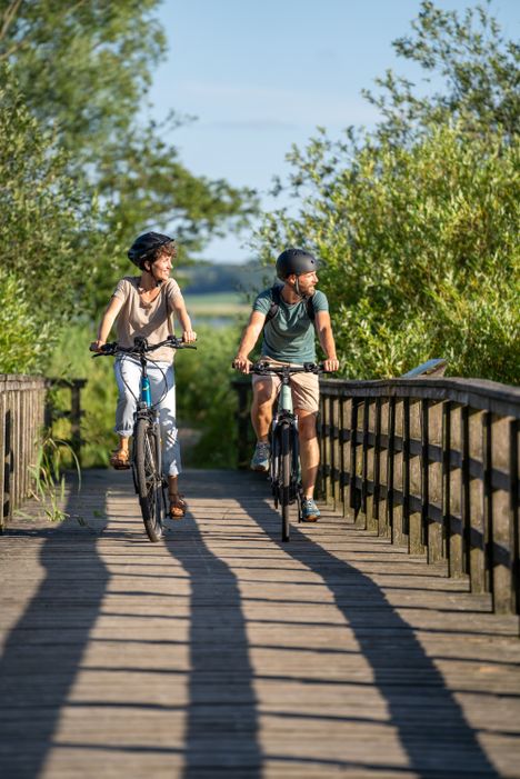 Paar fährt an einem Sommertag mit ihren Fahrradändern über eine Brücke.