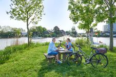 Paar ist mit dem Fahrrad an der Stör unterwegs und macht eine Pause auf einem Rastplatz mit Blick aufs Wasser.