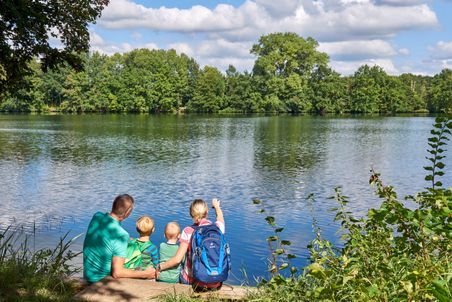 Familie sitzt am Ufer des Rensiger Sees und betrachtet das Waser