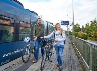 Radfahrer steigen aus eines Eisenbahn und schieben mit Ihrem Fahrrad auf dem Bahnsteig