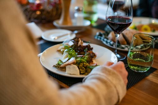 Frau genießt leckeres Abendessen mit einem Glas Rotwein